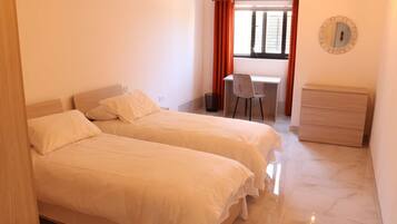 Une chambre avec deux lits, un bureau, une chaise et une commode.