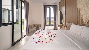 A hotel room with a large bed, a balcony, and a view of the city. - Triple Heaven Canggu (Canggu)