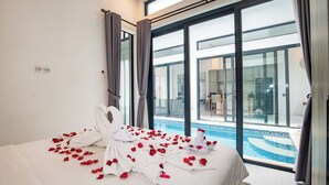 A hotel room with a bed, a large window, and a view of a swimming pool. - Triple Heaven Canggu (Canggu)