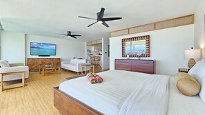 Une chambre d’hôtel comprenant un lit, un bureau, une chaise, une télévision, un ventilateur de plafond, un miroir et une fenêtre.