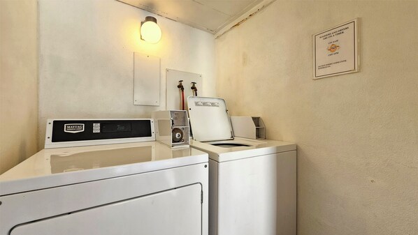 Un espace dédié à la blanchisserie, équipé d’une machine à laver Maytag de qualité professionnelle, d’un programmateur et d’un panneau indiquant les horaires de lavage et de séchage.