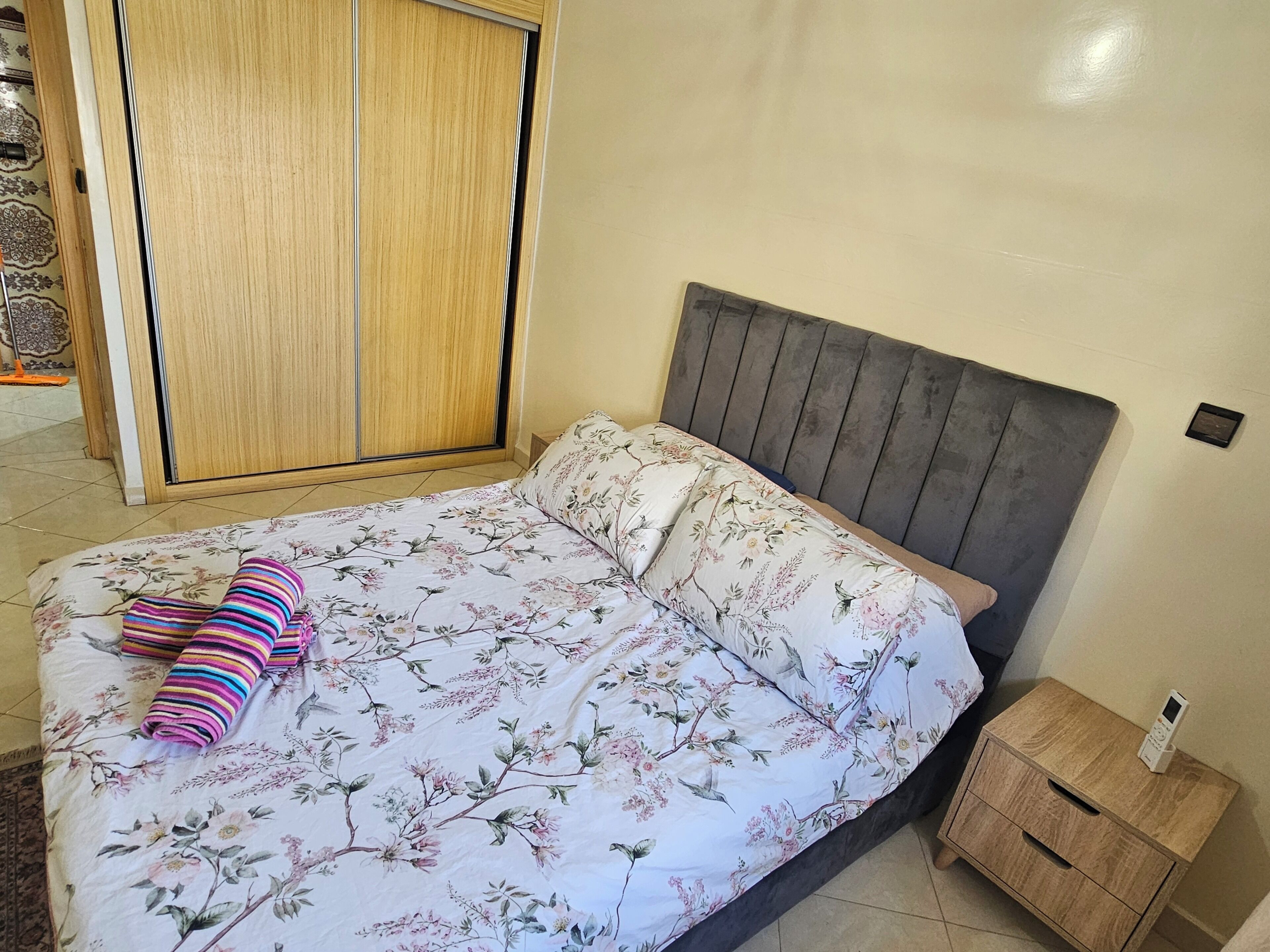 A bedroom with a bed, a nightstand, and a wardrobe.
