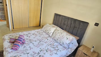 A bedroom with a bed, a nightstand, and a wardrobe.