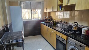 A kitchen with a washing machine, a stove, and cabinets. - Modern Casablanca Apartment – Parking, A/C & WiFi (Casablanca)