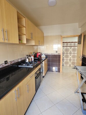 A kitchen with wooden cabinets, a black countertop, a stove, and a washing machine. - Modern Casablanca Apartment – Parking, A/C & WiFi (Casablanca)