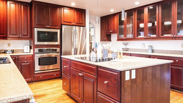 A modern kitchen with wooden cabinets, stainless steel appliances, and a granite countertop.