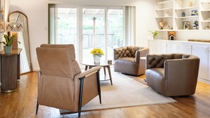A modern living room with leather armchairs, a round coffee table, and a bookshelf.