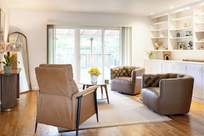 Una sala de estar moderna con sillones de cuero, una mesa de centro redonda y una estantería.
