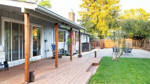 A wooden deck with a covered patio area, a fenced yard, and a small tree.