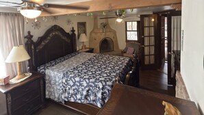 A bedroom with a bed, a nightstand, a dresser, a wooden ceiling, a fireplace, and a door leading to another room. - Downtown, Old Town, Sawmill, 2-bedroom home in ABQ, additional parking available (Albuquerque)