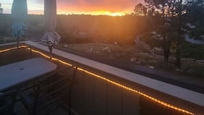 Ein Balkon mit Blick auf einen Sonnenuntergang, einem Tisch und Stühlen.