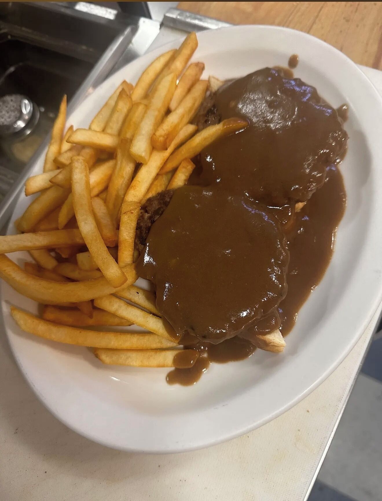 A plate with French fries and a meat patty covered in gravy.