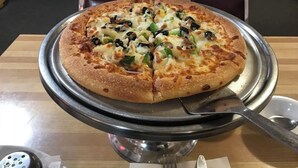 A pizza on a metal tray with a fork and knife beside it. - Alliance valley Inn motel (Alliance)