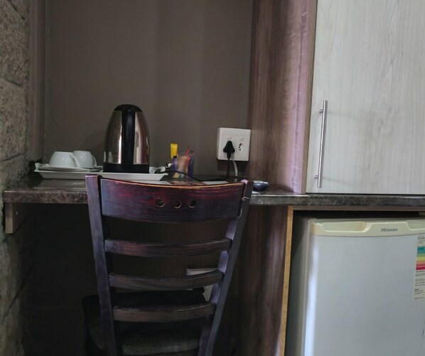 Cocina pequeña equipada con refrigerador, cafetera y una silla.