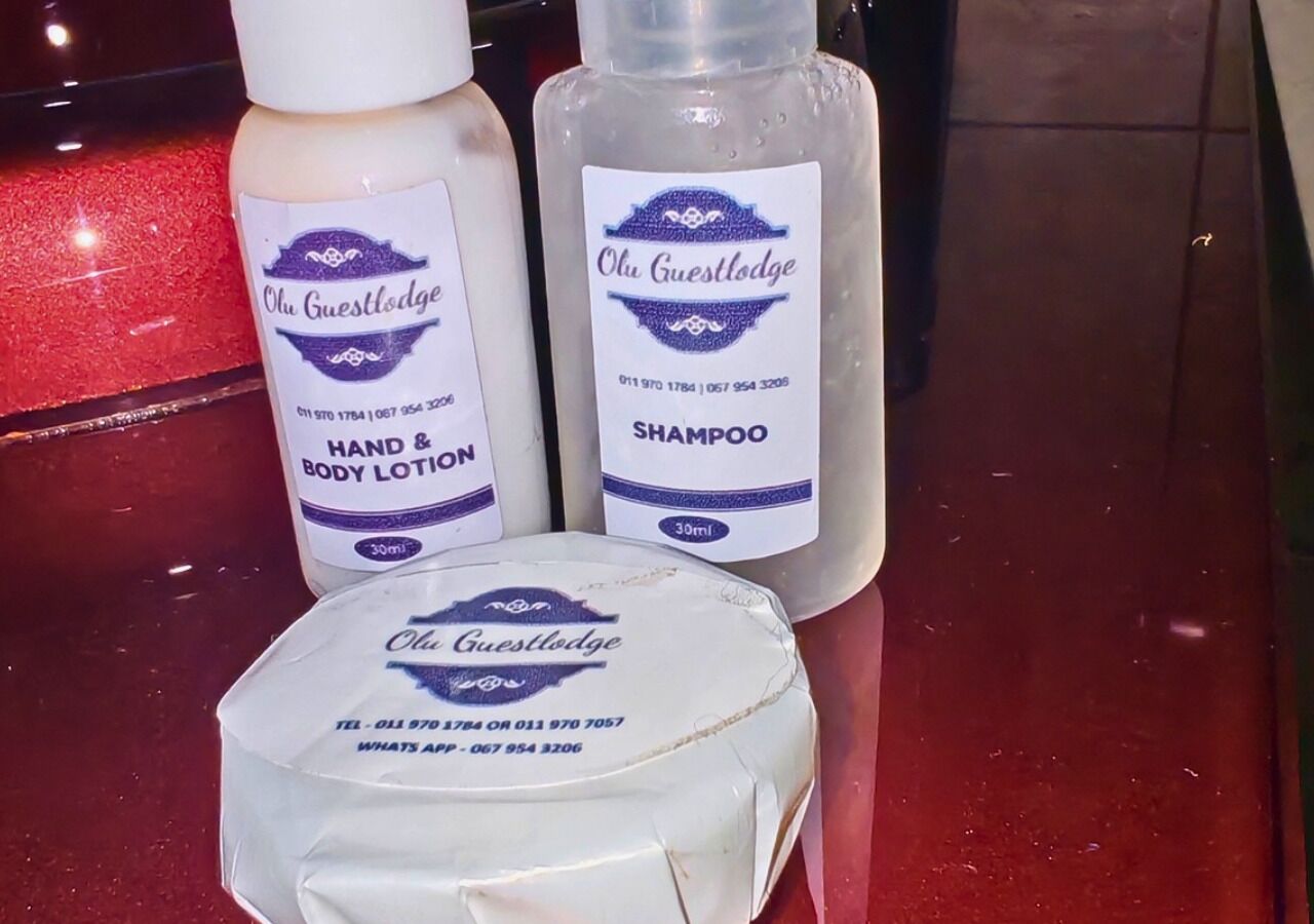 A bottle of hand and body lotion, a bottle of shampoo, and a bar of soap, all labeled with 'Olu Guest Lodge' branding.