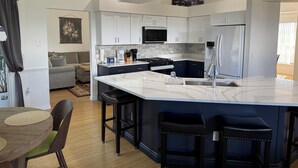A modern kitchen with white cabinets, a marble island, and a stainless steel refrigerator. - Beautiful 3-bedroom Vacation Home located in beautiful Brooksville Fl (Spring Hill)