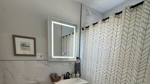 A bathroom with a toilet, sink, mirror, and shower curtain.