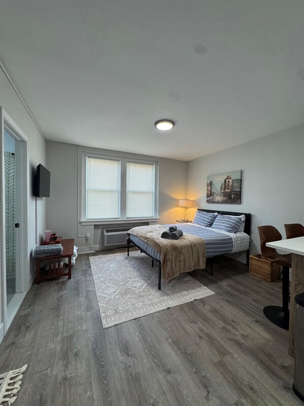 A compact bedroom with a bed, bedside table, lamp, and a painting on the wall.