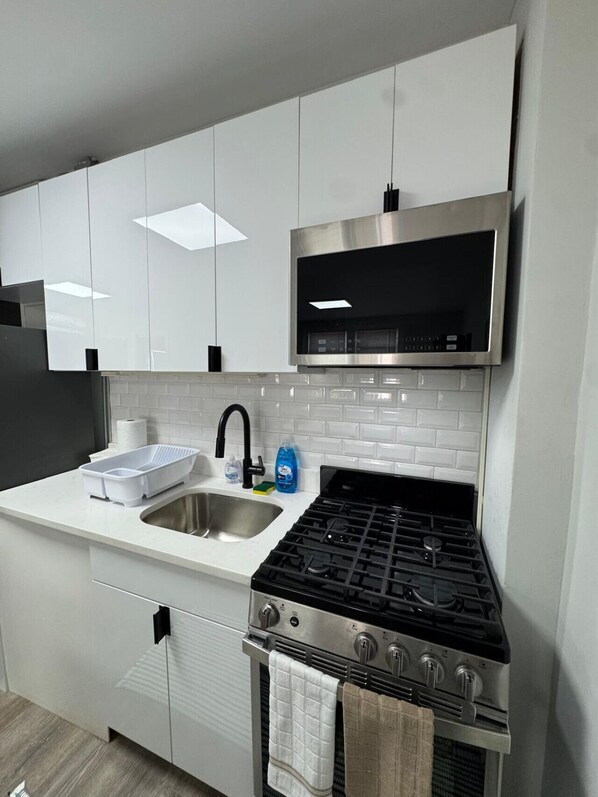 Una cocina moderna con armarios blancos, una estufa de acero inoxidable y un grifo negro.