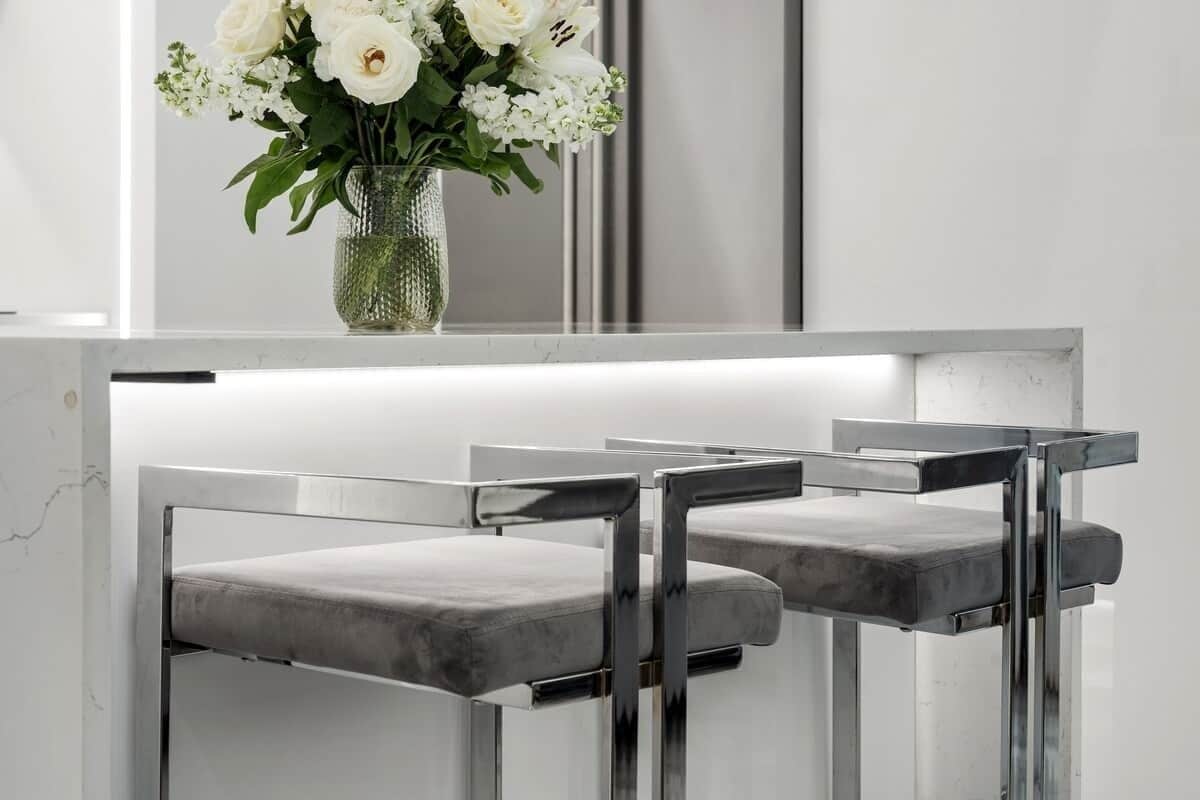 Un taulell de recepció modern amb un ram de flors blanques, dues cadires tapissades de color gris i una superfície reflectant.