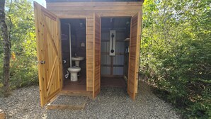 Eine hölzerne Außentoilette mit Waschbecken und Tür.