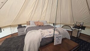 Ein Zelthaus mit Bett, einer Willkommensschild und einem kleinen Tisch mit Stuhl.