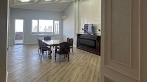 Amplia habitación con mesa y sillas de comedor, chimenea y un ventanal grande.