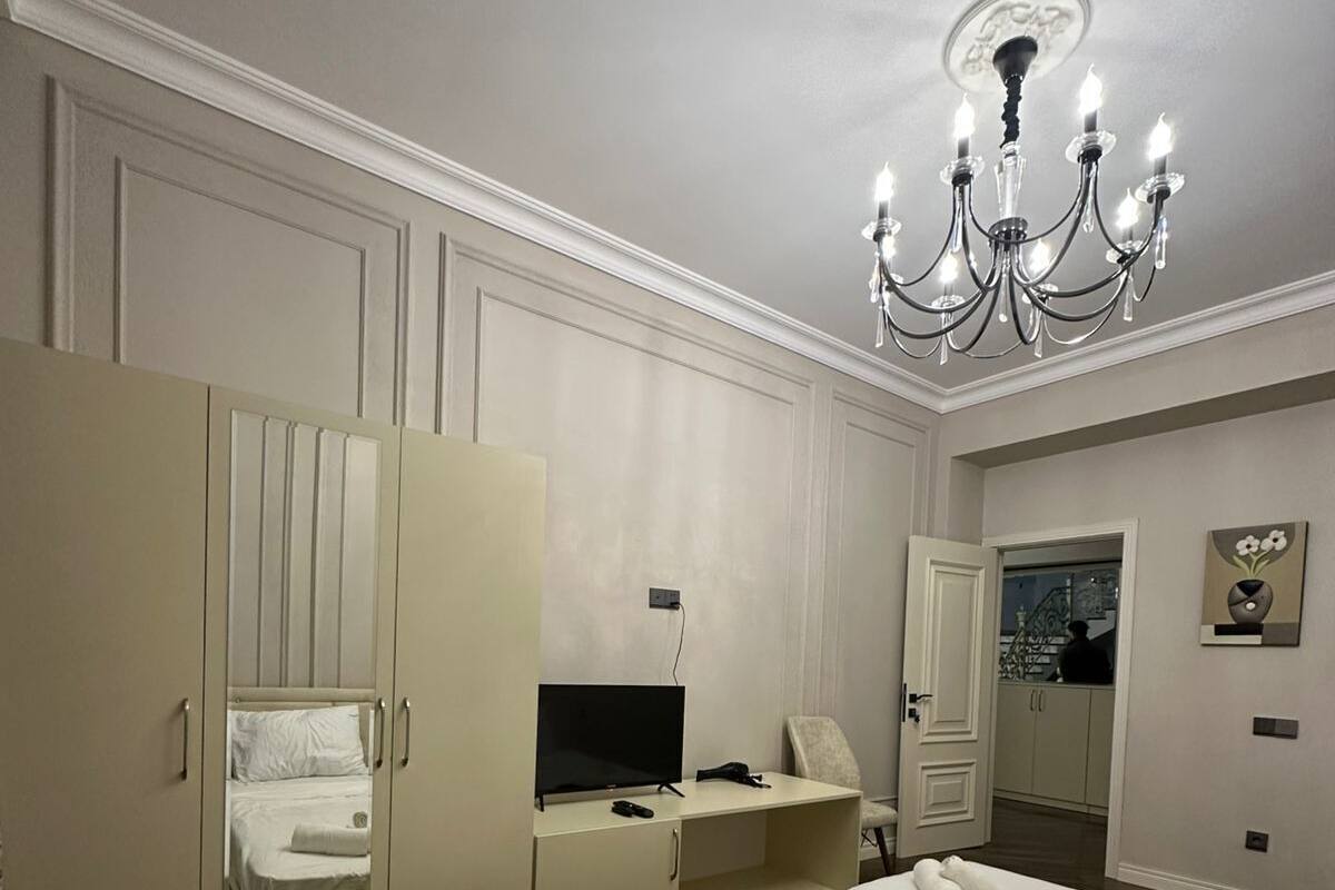 Une chambre d’hôtel avec deux lits, une télévision, un bureau et un lustre.