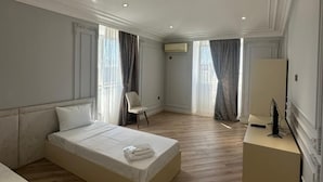 Una habitación de hotel con una cama grande, un escritorio, una silla y un televisor.