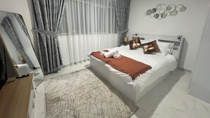 Una camera d'albergo con un letto grande, un comodino, uno specchio e una lampada a parete.