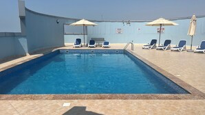 Una piscina con lettini e ombrelloni, circondata da un muretto.