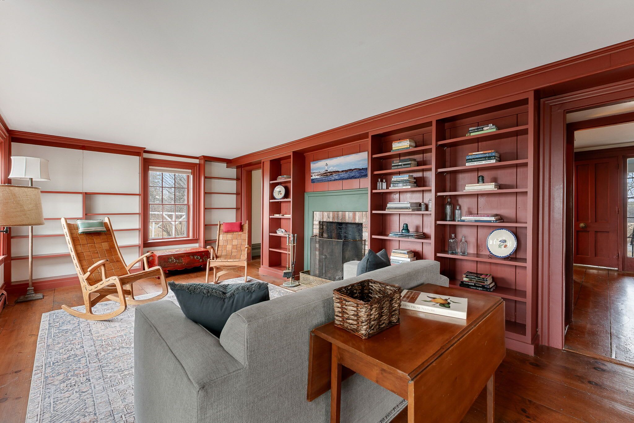 A living room with a fireplace, bookshelves, a sofa, a rocking chair, and a lamp.