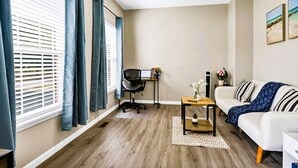 Un salón moderno con un sofá blanco, una mesa de centro de madera y un escritorio con una computadora.
