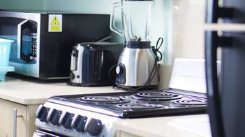 Una cocina equipada con estufa, microondas, tostadora y licuadora.