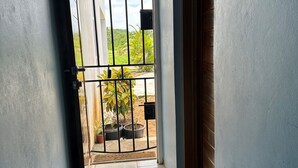 A hallway with a tiled floor, a brown doormat, and a metal gate leading to a garden with potted plants. - Private Oasis - Portland’s Coastal Gated Hideaway (Fair Prospect)
