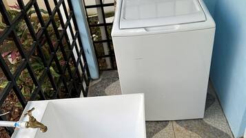 A white washing machine and a white sink with a faucet.