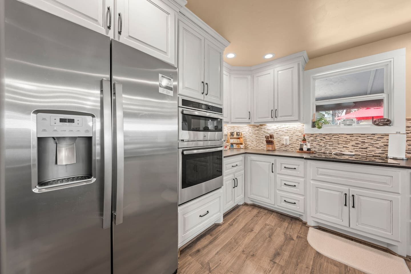 A modern kitchen with stainless steel appliances, white cabinetry, and a built-in water dispenser.