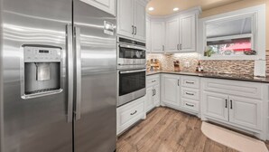 Una cocina moderna con electrodomésticos de acero inoxidable, armarios blancos y un dispensador de agua integrado.