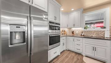 A modern kitchen with stainless steel appliances, white cabinetry, and a built-in water dispenser.