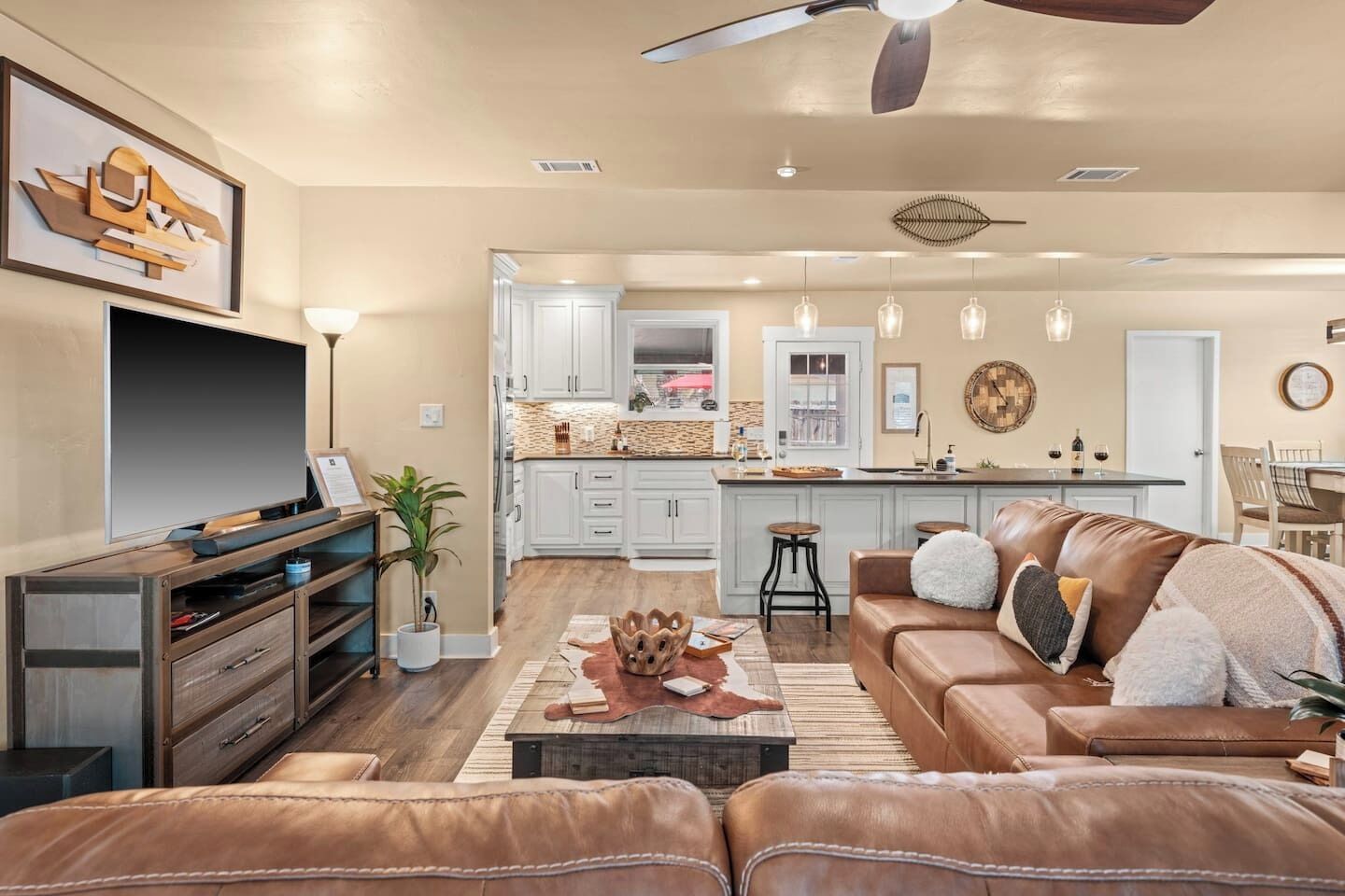 A modern living room with a brown leather sofa, a flat-screen TV, and a wooden coffee table.