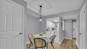 Un coin repas comprenant une table ronde, quatre chaises et un luminaire suspendu.
