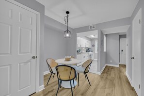 A dining area with a round table, four chairs, and a hanging light fixture.