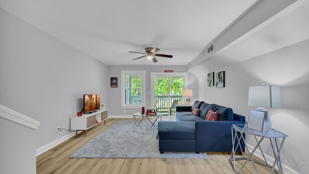 Un salon moderne avec un téléviseur, un canapé et un ventilateur de plafond.
