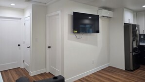 Eine moderne Küche mit weißen Wänden, einem integrierten Kühlschrank und einem an der Wand befestigten Fernseher.