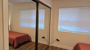 Ein Zimmer mit zwei Betten, Holzboden und Fenstern mit Jalousien.