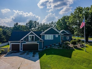 A two-story house with a garage, a well-maintained lawn, and an American flag.