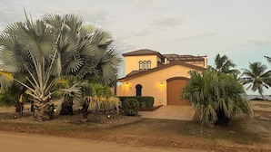 Un edificio de dos plantas con fachada color beige, techo marrón y una pequeña entrada en arco.