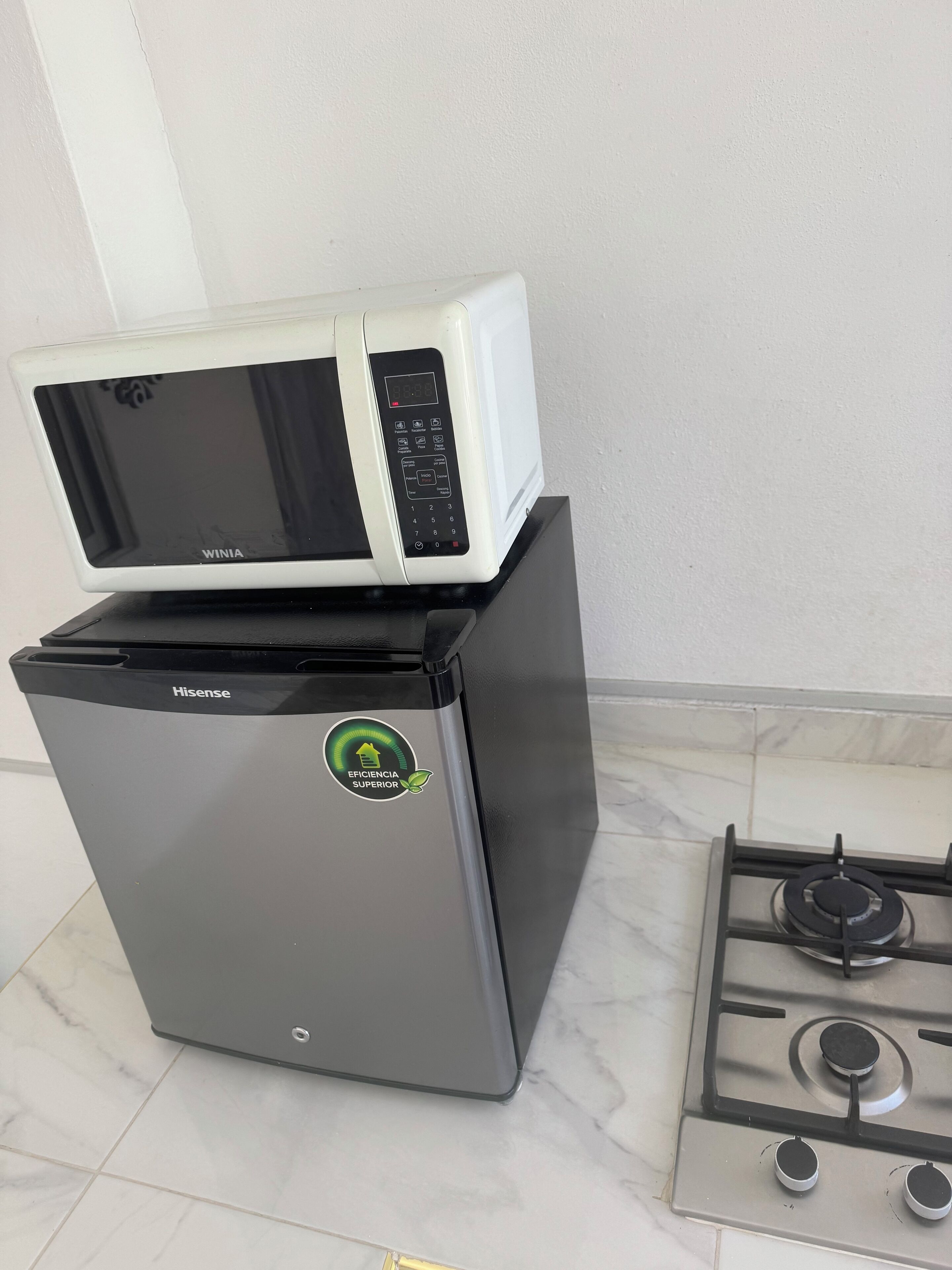 A compact kitchen with a Hisense refrigerator, a white microwave, and a gas stove.