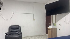 A room with a massage chair, a TV mounted on the wall, a sink, and two beds. - Cozy house near the beach (Mazatlan)