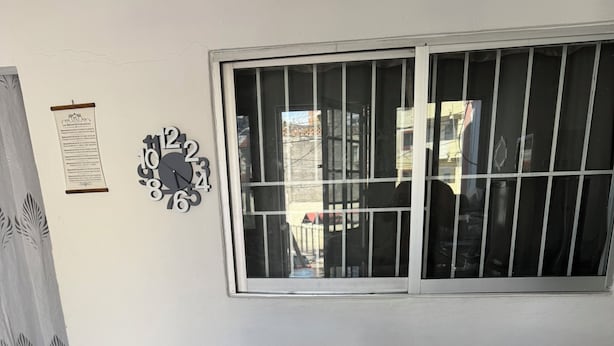 A modern kitchen with a marble countertop, three bar stools, and a window with metal bars. - Cozy house near the beach (Mazatlan)